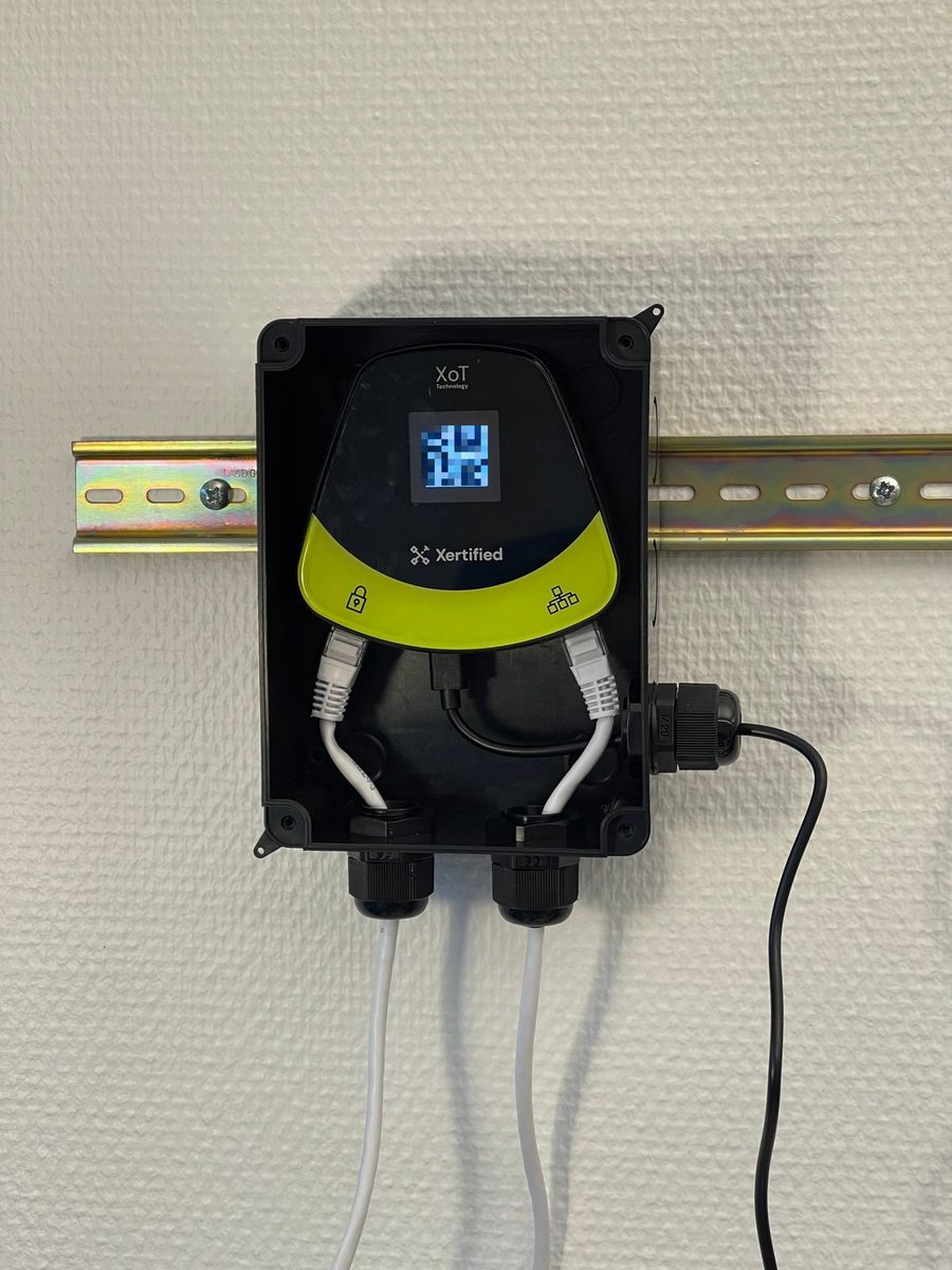 An XoT-S1 in an enclosure on a DIN rail. The network and power cables exit through the bottom.